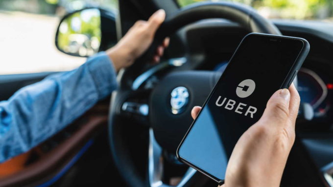 Motorista segurando celular com app Uber aberto