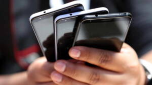 Pessoa segurando três celulares nas mãos